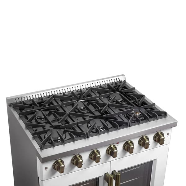 Left-angled view of the cooktop on the FORNO Galiano 36-Inch French Door Gas Range in white, showcasing six sealed brass burners, heavy-duty cast iron grates, and precise control knobs with brass accents.