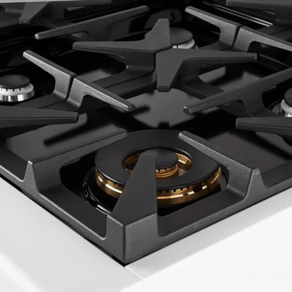 Close-up of a brass burner on the Forno Antico 36-Inch Dual Fuel Range in white, featuring precise flame ports and durable cast iron grates for efficient heat distribution and premium performance.