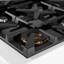 Close-up of a brass burner on the Forno Antico 36-Inch Dual Fuel Range in white, featuring precise flame ports and durable cast iron grates for efficient heat distribution and premium performance.