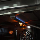 Close-up of a lit broiler burner inside a FORNO gas oven, showing the flame element and convection fan in the oven cavity.
